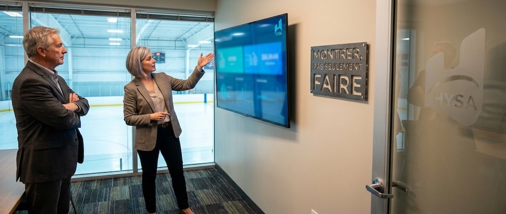 Aréna municipal québécois, gestionnaire présentant l’historique d’entretien à une direction sur grand écran